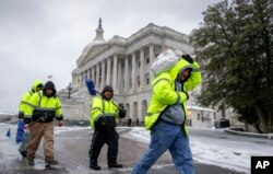 Workmen clear snow on Capitol Hill in Washington, March, 14, 2017.