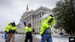 واشنگٹن ڈئ سی میں کارکن کیپیٹل ہل کے قریب برف ہٹانے جا رہے ہیں۔ 14 مارچ 2017