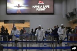Workers wearing protective gear spray disinfectant as a precaution against the coronavirus outbreak, in the departure terminal at the Rafik Hariri International Airport, in Beirut, Lebanon, Thursday, March 5, 2020.