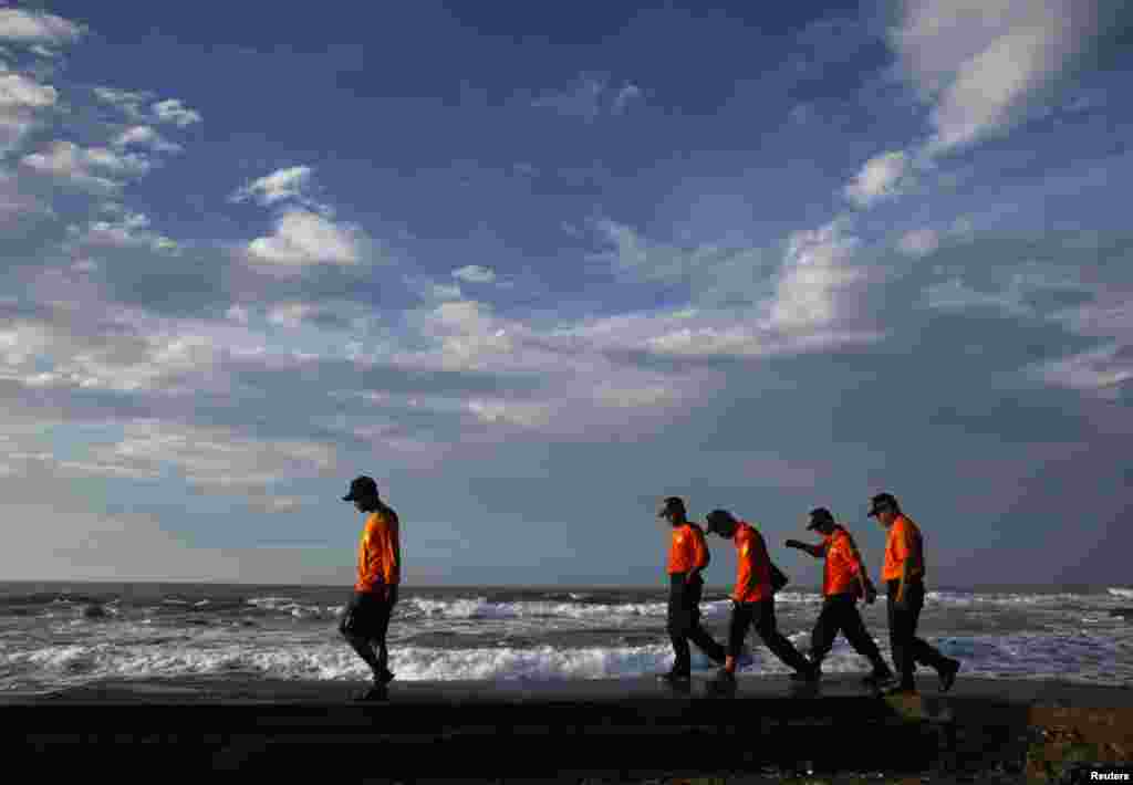 Rescue workers walk along the beach as they search for suspected asylum seekers who were on a boat that capsized, Sukapura beach in West Java, Indonesia, July 25, 2013.