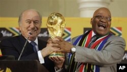 South African President Jacob Zuma, right, laughs as he hands over the trophy to FIFA President Joseph Blatter, left, during the briefing to local and international media on the 2010 Soccer World Cup at the Presidential Guest House in Pretoria, South Afri
