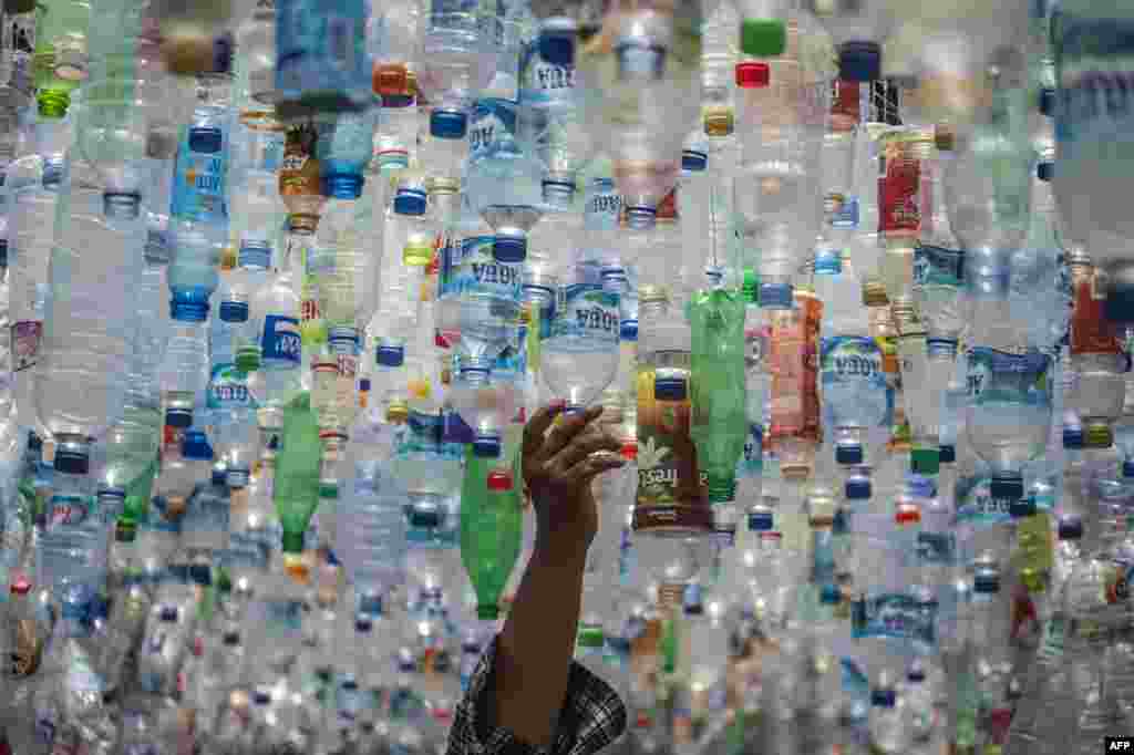 An Indonesian activist from ECOTON (Ecological Observation and Wetland Conservation) prepares an installation made with used plastic, including 4,444 bottles, collected from the river in Gresik.