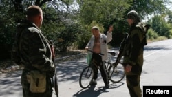 Pro-Russian separatists talk to a local resident at a check point on the outskirts of Donetsk, Sept. 6, 2014.