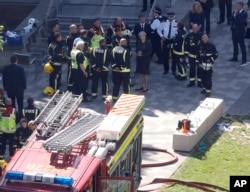 Britain's Prime Minister Theresa May, center, speaks with firefighters after arriving at Grenfield Tower in London, June 15, 2017, following a deadly fire in the apartment block.