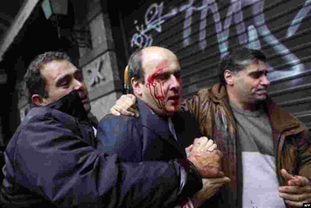 A bodyguard, left, leads off former Greek development minister Costis Hatzidakis, center, after he was attacked by protesters in Athens, Wednesday Dec. 15, 2010. Protesters clashed with riot police across Athens on Wednesday, torching cars, hurling gasoli