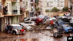 Residents look at cars piled up after being swept away by floods in Valencia, Spain, Oct. 30, 2024.