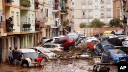 Warga melihat mobil-mobil yang menumpuk setelah tersapu banjir di Valencia, Spanyol, 30 Oktober 2024.