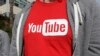 FILE—This April 4, 2018, photo shows a YouTube logo on a t-shirt worn by a person near a YouTube office building in San Bruno, Calififornia. 