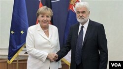 Kanselir Jerman Angela Merkel (kiri) berjabat tangan dengan PM Serbia Mirko Cvetkovic saat berkunjung ke Belgrade, Serbia (23/8).