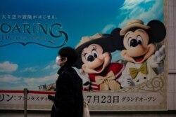 A man wearing a mask walks past an advertisement for the Tokyo Disney Resort at a train station in Urayasu, near Tokyo, Feb. 28, 2020. The amusement park will be closed Feb. 29 to March 15 in an effort to prevent the spread of COVID-19.