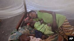 FILE - Two children and their mother rest under a mosquito net in the small village of Walikale, Congo.