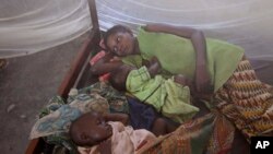 FILE - Two children and their mother rest under a mosquito net in the small village of Walikale, Congo, Sept. 19, 2010.