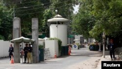 FILE - A policeman (2nd R) and private security personnel stand guard at the entrance of a road leading towards the U.S. consulate in Lahore.