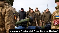 Ukrainian President Volodymyr Zelensky examines weapons as he attends tactical military exercises held by the country's armed forces at a training ground in the Rivne Region, February 16, 2022. (Ukrainian Presidential Press Service/Reuters)