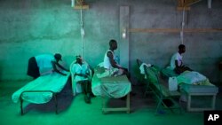 The daughter of 84-year-old Armant Germain replaces the sheets on her bed, in the cholera ward at a hospital in Les Cayes Haiti, Oct. 11, 2016. 