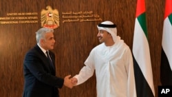 Menteri Luar Negeri Israel Yair Lapid berjabat tangan dengan Menteri Luar Negeri Uni Emirat Arab Sheikh Abdullah bin Zayed al-Nahyan di Abu Dhabi, Uni Emirat Arab, Selasa, 29 Juni 2021. (Shlomi Amsalem/Government Press Office via AP)