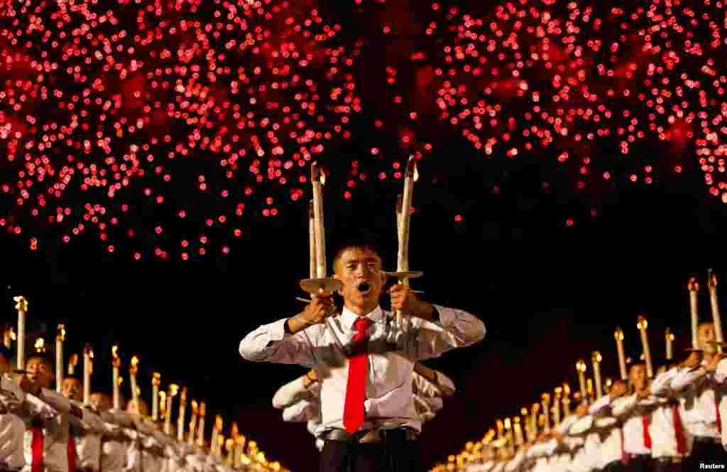 Fireworks explode over participants carrying torches during a torchlight procession during the celebration marking the 70th anniversary of North Korea&#39;s foundation in Pyongyang, North Korea.