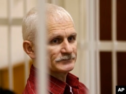 FILE - Ales Bialiatski, the head of Belarusian Viasna rights group, stands in a defendants' cage during a court session in Minsk, Belarus, on Nov. 2, 2011.