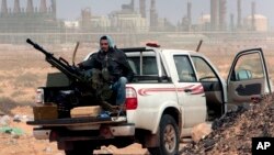 FILE - An anti-government rebel sits with an anti-aircraft weapon in front an oil refinery in Ras Lanouf, eastern Libya, March 5, 2011. The United States, France, Germany, Italy, Spain and Britain have called upon forces loyal to a Libyan general to withdraw from three eastern oil terminals seized earlier this week, in a statement, Sept. 13, 2016.