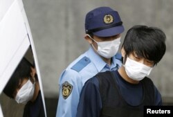 Tetsuya Yamagami, yang diduga membunuh mantan PM Jepang Shinzo Abe, dikawal oleh seorang polisi di kantor polisi Nara-nishi di Jepang barat, 10 Juli, 2022. (Kyodo via REUTERS