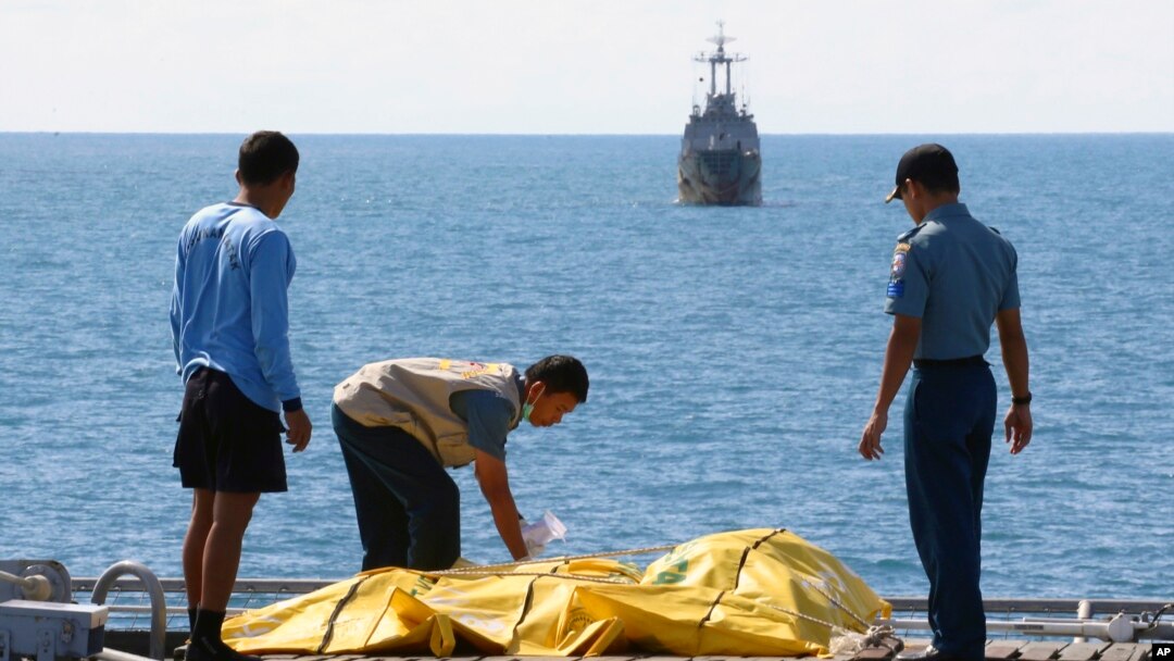 Para anggota tim pencari korban AirAsia memeriksa kantung jenazah di dek kapal Angkatan Laut KRI Banda Aceh, di laut Jawa, Indonesia (23/1).
