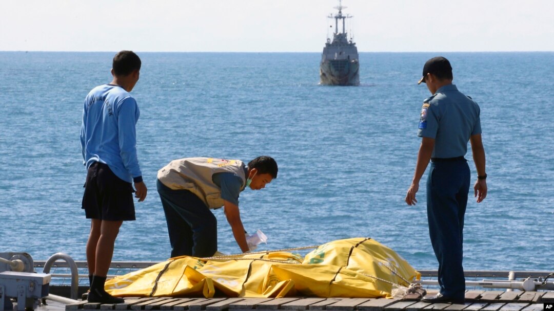 Beberapa anggota Basarnas memeriksa jenazah penumpang korban pesawat AirAsia (foto: dok). 92 korban tewas belum ditemukan di perairan Laut Jawa.