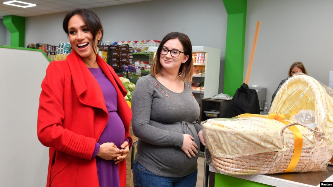 Meghan, Duchess of Sussex, memberikan sebuah keranjang Angela Midgley sebuah keranjang bayi di sebuah supermarket warga dan komunitas di Birkenhead, di Inggris, 14 Januari 2019. 