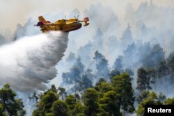 Avião de combate a incêndios despeja água sobre as chamas junto da vila de Ellinika, ilha de Evia, Grécia, 8 Agosto, 2021.