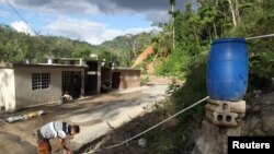 Un hombre extrae agua de un tanque de plástico en Utuado, Puerto Rico, en febrero de 2018, casi medio año después del paso del Huracán María por la isla.