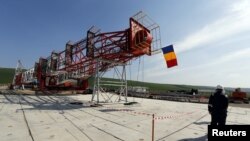 FILE - A worker walks in front of the drilling tower at Chevron's site during a media day in Pungesti.