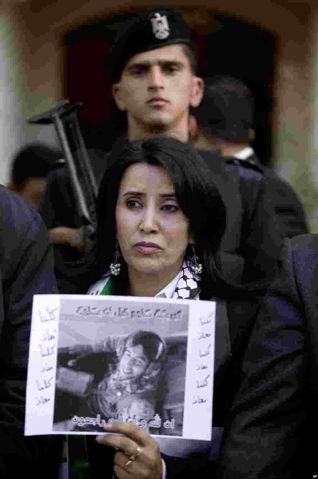 A Palestinian woman holds a poster with a picture of slain Jordanian pilot, Lt. Muath al-Kaseasbeh during a protest in front of the Jordanian embassy, in the West Bank City of Ramallah, Feb. 4, 2015.