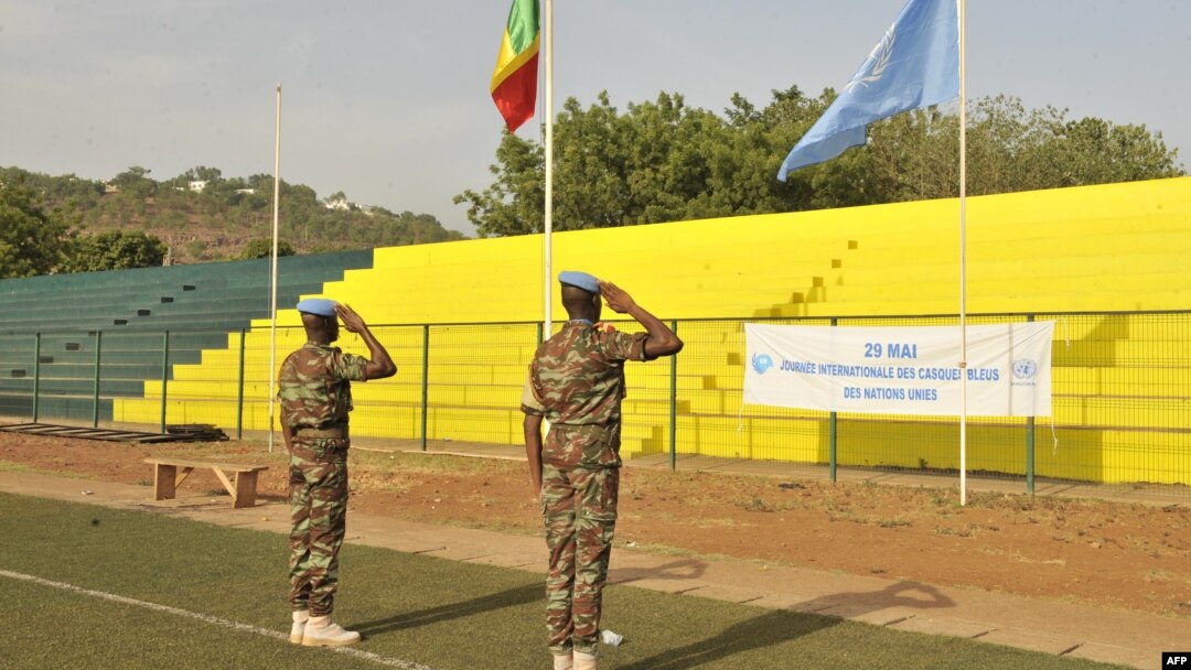 Peacekeepers of the United Nations Multidimensional Integrated Stabilization Mission in Mali (MINUSMA) salute Mali and UN flags on May 29, 2015, in Bamako.