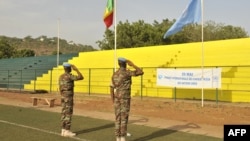 Peacekeepers of the United Nations Multidimensional Integrated Stabilization Mission in Mali (MINUSMA) salute Mali and UN flags on May 29, 2015, in Bamako.