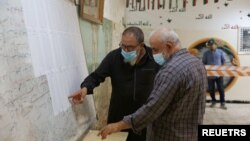 FILE - People check names to receive their voter cards inside a polling station in Tripoli, Libya, Nov. 8, 2021.