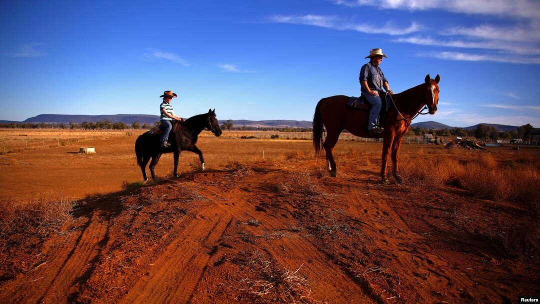 FILE - Farmer Scott Cooper and his daughter Charlie ride their horses along a fence in a drought-affected paddock on their property named "Nundah," south of the central New South Wales town of Gunnedah in Australia, July 21, 2018.