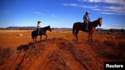 FILE - Farmer Scott Cooper and his daughter Charlie ride their horses along a fence in a drought-affected paddock on their property named "Nundah," south of the central New South Wales town of Gunnedah in Australia, July 21, 2018.