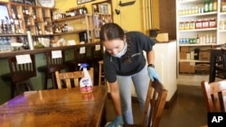 Carlee Packard wipes down a table and chairs after customers finished eating at Puckett's Grocery & Restaurant, April 27, 2020, in Franklin, Tenn. 