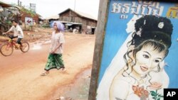 Cambodians in Anlong Veng, the former stronghold of the Khmer Rouge, walk past a wedding shop advertisement.