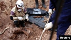 Activists and rebel fighters remove buried bodies in one of the headquarters of the Islamic State in Iraq and the Levant (ISIL), that had been an ISIL stronghold before it was captured by rival rebel forces, beside Bureij roundabout on the road to Sheikh 