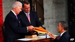 Avant de prononcer son discours dans l'enceinte du Capitole, le président Obama (à dr.) en remet le texte, comme le veut la tradition, au vice-président Joseph Biden (à g.), à titre de président du Sénat, et au républicain John Boehner, président de la Ch