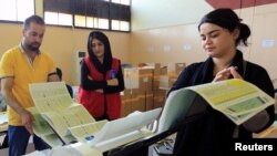 Employees of the Iraqi Independent High Electoral Commission check an electronic counting device at a warehouse in Dohuk, Iraq, May 16, 2018. 