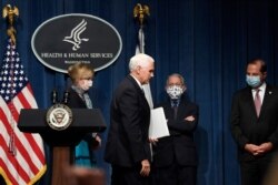 Vice President Mike Pence, second from left, walks off of the stage following the conclusion of a briefing with the Coronavirus Task Force at the Department of Health and Human Services in Washington, June 26, 2020.