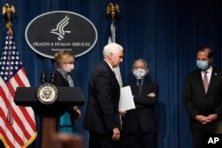 Vice President Mike Pence, second from left, walks off of the stage following the conclusion of a briefing with the Coronavirus Task Force at the Department of Health and Human Services in Washington, June 26, 2020.