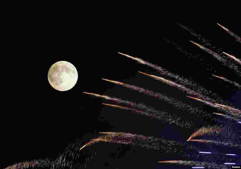 Fireworks streak past in front of the supermoon outside the town of Mosta, celebrating the feast of its patron saint, in central Malta, Aug. 10, 2014.