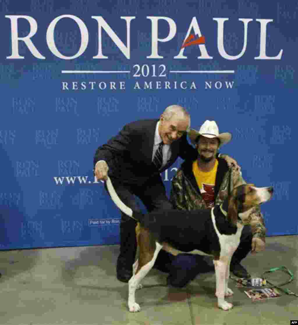 Republican presidential candidate, Rep. Ron Paul, R-Texas, poses with Jon Hathaway as he holds up the tail of his dog Tizzy during a photo line at a campaign event at the Iowa State Fair Grounds in Des Moines, Iowa, Wednesday, Dec. 28, 2011. (AP Photo/Cha