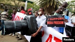 A Kenyan journalist carries a giant plastic replica of a camera as he participates in a protest in the capital Nairobi, Dec. 3, 2013. 