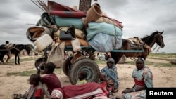 FILE - A Sudanese family who fled the conflict in Murnei in Sudan's Darfur region, sit beside their belongings while waiting to be registered by UNHCR upon crossing the border between Sudan and Chad in Adre, Chad, July 26, 2023.