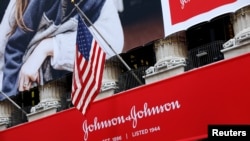 FILE - The U.S. flag is seen over the company logo for Johnson & Johnson to celebrate the 75th anniversary of the company's listing at the New York Stock Exchange (NYSE) in New York, Sept. 17, 2019.