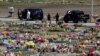 Un empleado de una funeraria y miembros de la Policía Militar son fotografiados en un cementerio antes del entierro de una víctima del coronavirus.