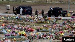 Un empleado de una funeraria y miembros de la Policía Militar son fotografiados en un cementerio antes del entierro de una víctima del coronavirus.